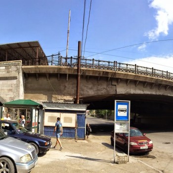 Справа - мост над проспектом Аршакуняц, по которому проходит состав. Слева сверху - начало навеса над платформой станции. Слева внизу - вход в вестибюль. За фотографом - площадь Труда.